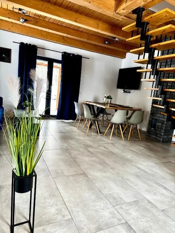 Salon z widokiem na okna tarasowe, rośliny w donicach i schody
