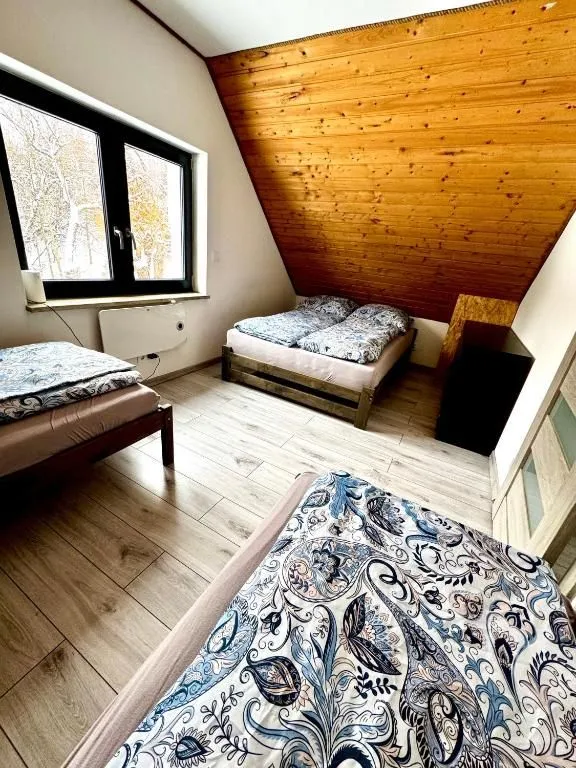 Druga sypialnia z łóżkami pod drewnianym skosem i oknem